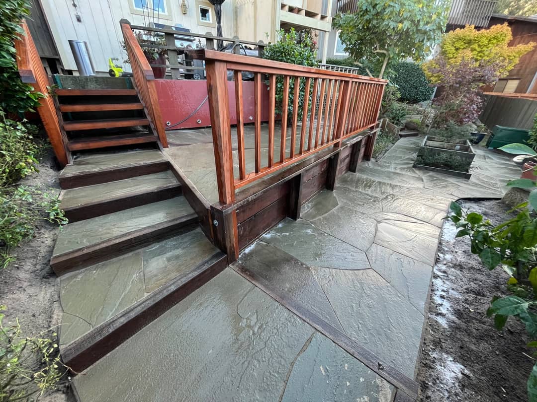 A hardwood deck with a matching railing, set above a flagstone patio